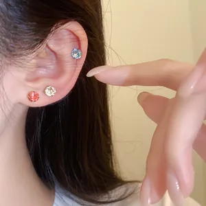 Gedetailleerde close-up van kleurrijke ronde roestvrijstalen oorknopjes op het oor gedragen