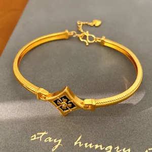 Detalle de brazalete floral chapado en oro con esmalte negro e incrustación de circón