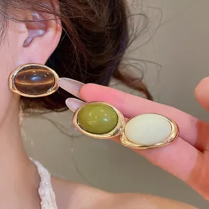 Elegant resin oval earrings with gold-tone border, featuring multiple colors.