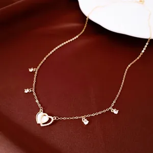 Detail view of 14k gold plated heart necklace with zircon and shell pendants.