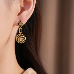 Detalle de elegantes pendientes de flores chapados en oro con esmalte negro y circones