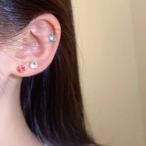 Close-up detail van drie kleurrijke strass oorknopjes gedragen op het oor van een model