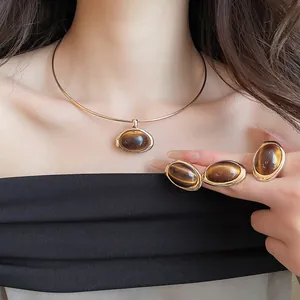 Detailaufnahme eines eleganten Schmucksets mit braunen ovalen Harzsteinen an Model