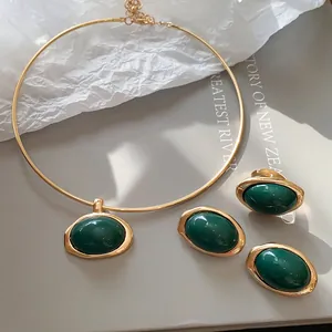 Detail eines grünen Harz-Schmucksets mit ovaler Halskette, Ohrringen und Ring in Gold.