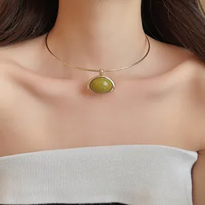 Nahaufnahme eines minimalistischen Goldhalsreifs mit elegantem grünem Harzanhänger