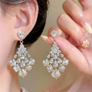 Close-up detail of elegant gold-toned chandelier earrings with teardrop rhinestones.