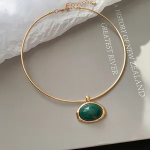 Detailansicht einer minimalistischen goldenen Halskette mit grünem Harzanhänger