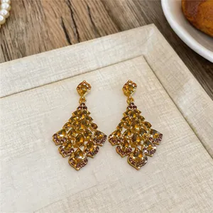 Detail view of elegant gold chandelier earrings with amber teardrop stones.