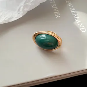 Detaillierte Nahaufnahme eines luxuriösen ovalen Rings aus grünem Harz mit Goldfassung
