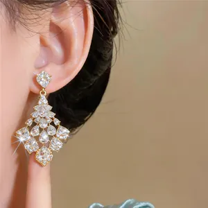 Close-up view of elegant gold-toned fan-shaped earrings with sparkling teardrop diamonds