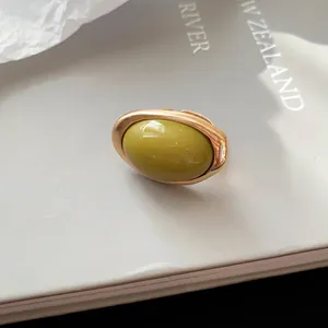 Detailansicht eines ovalen olivgrünen Harzrings im Vintage-Stil mit goldenem Metallrahmen