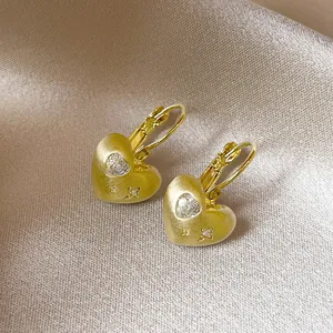 Detail van 18k vergulde hartvormige oorbellen met hart-zirkonia en gegraveerde sterren