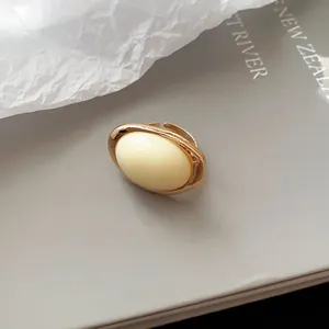 Nahaufnahme eines eleganten Goldrings mit einem cremefarbenen ovalen Harz-Mittelstück