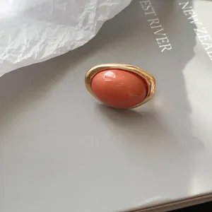 Detailaufnahme eines ovalen Korallenharzrings im Vintage-Stil mit einem Goldmetallrahmen
