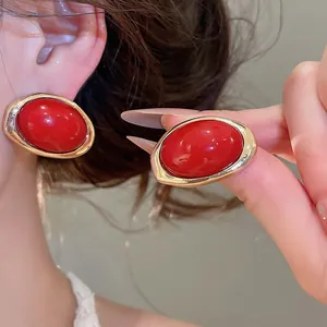 Detailaufnahme roter ovaler Harzohrringe mit eleganten goldfarbenen Rändern.