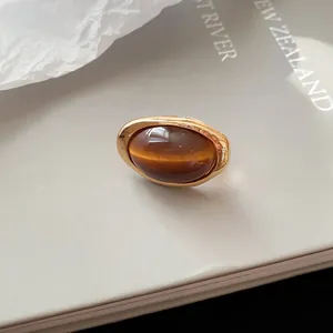 Detailansicht eines goldenen Vintage-Rings mit ovalem bernsteinfarbenem Harzstein.