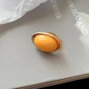 Nahaufnahme eines eleganten Goldrings mit einem leuchtend orangefarbenen Harzinlay