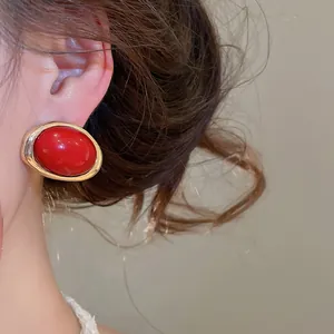 Nahaufnahme eines roten Vintage-Resin-Ohrrings, getragen am Ohr eines Models