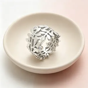Vue détaillée d'une bague large en acier avec feuilles d'olivier ajourées et diamants