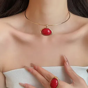 Nahaufnahme von elegantem goldenem Choker und passendem Ring mit roten ovalen Harzsteinen