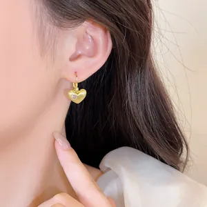 Close-up van een elegante 18k vergulde hartvormige oorbel met zirkoonsteentjes