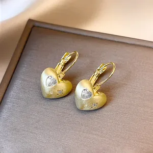 Detailopname van vergulde hartoorringen met fonkelende zirkonia-details van hart en ster.