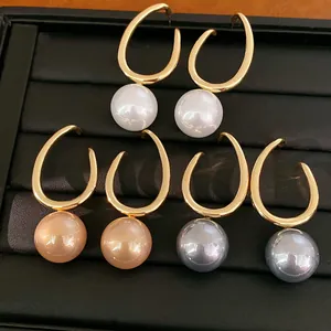 Detailed view of geometric gold hoop earrings with white, peach, and grey pearls