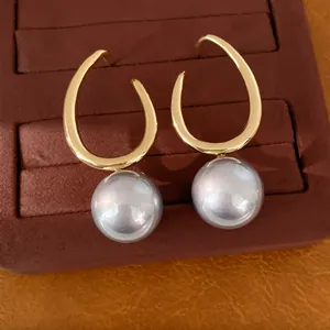 Detail view of elegant gold geometric hook earrings with round lavender pearls on a velvet tray.
