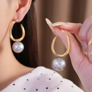 Elegant geometric gold hoop earrings featuring large lustrous grey pearl drop details