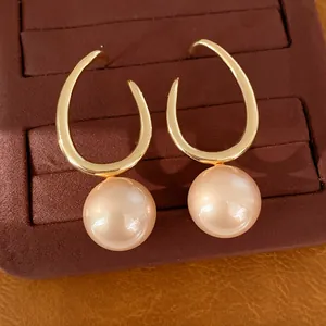 Elegant close-up of geometric gold earrings featuring large champagne round pearls