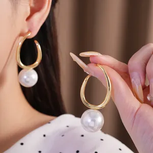 Detailed view of elegant geometric gold hoop earrings with white pearl pendants