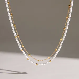 Detailed view of a double-layered stainless steel necklace with pearls and gold beads.