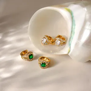 Gros plan de boucles d'oreilles en acier doré avec zircon vert dans un coquillage