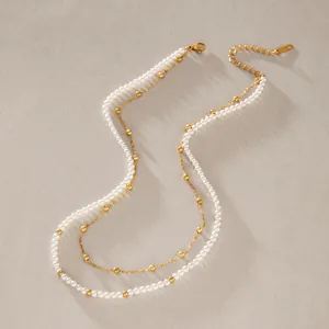 Close-up of double-layered stainless steel necklace with white pearls and gold beads