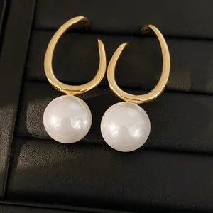 Detailed macro view of geometric gold hoop earrings with elegant large round pearls.