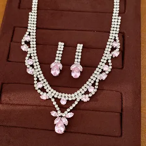 Detailed view of luxury pink zircon teardrop necklace and earring set on brown velvet