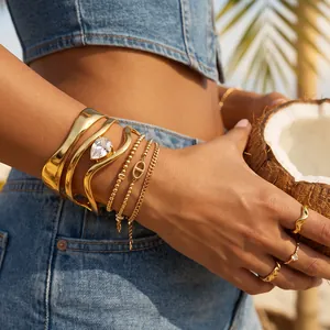 Detail van onregelmatige gouden roestvrijstalen armbanden ingelegd met zirkoon steen.
