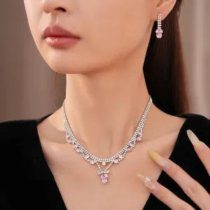 Close-up of elegant zircon necklace and earrings set with pink water drop pendants