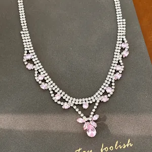 Detailed macro view of a sparkling pink teardrop cubic zirconia pendant on a crystal necklace