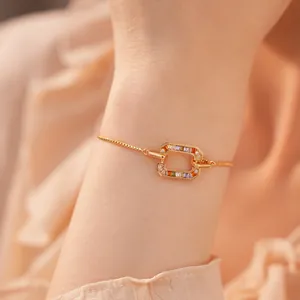 Detailweergave van 18k vergulde vierkante armband met gekleurde zirkoonstenen om de pols