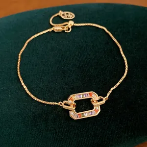 Gedetailleerde weergave van 18k vergulde armband met gekleurde zirkoon op groen fluweel.