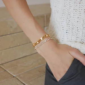 Detailansicht eines Titanium-Goldarmbands mit Dreieck-Zirkonia und Tennisarmband am Handgelenk.
