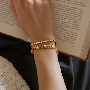 Detailansicht eines goldfarbenen Dreieck-Zirkonia-Armbands und eines Tennisarmbands