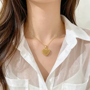 Detail shot of a gold hollow heart pendant necklace worn with a white sheer shirt