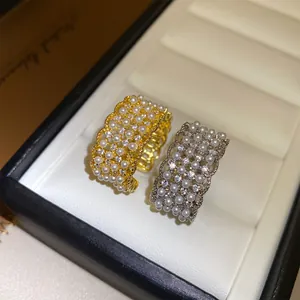 Detailopname van opengewerkte kanten ringen met parels en zirkonia in goud en zilver