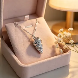 Detailed view of a silver stainless steel conch shell pendant necklace in a pink box