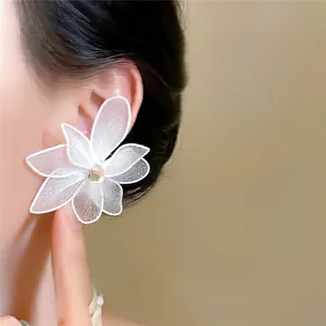 Detailopname van een elegante witte mesh bloemoorbel met zirkoon op het oor van een model