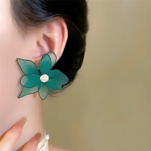 Detailopname van elegante groene mesh bloem oorknopjes met een centrale zirkoonsteen