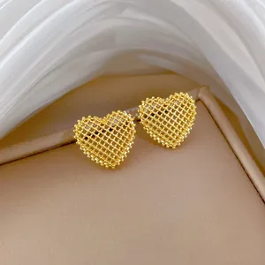 Detailed view of elegant gold heart stud earrings with a sophisticated hollow mesh design
