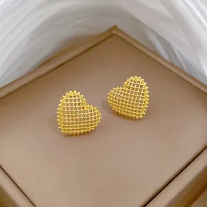 Detailed macro view of elegant gold-plated hollow mesh heart stud earrings for women